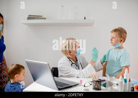 Doctor taking a sample from a boy's throat using a cotton swab Stock Photo