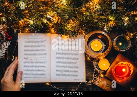 open book on rustic wooden board xmas tree branch. Reading Christmas fairytale Story. Christmas Holiday mood. New Year light, Hygge cozy home interior Stock Photo