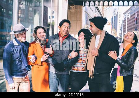 Six Millennial friends walk arm in arm in they city during cold weather - Holidays - Concept Good times Stock Photo
