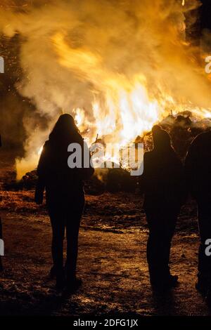 Silhouette of people standing in front of a big fire Stock Photo