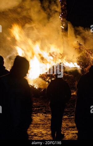 Silhouette of people standing in front of a big fire Stock Photo