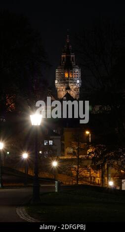 City night scene with road and streetlights in foreground and the cathedral of Mainz in the background Stock Photo