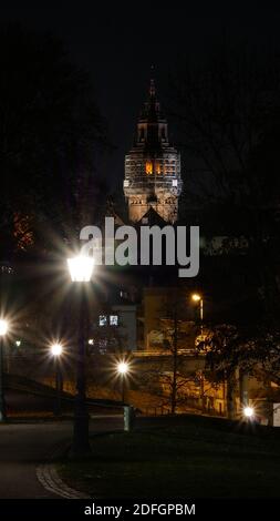 City night scene with road and streetlights in foreground and the cathedral of Mainz in the background Stock Photo