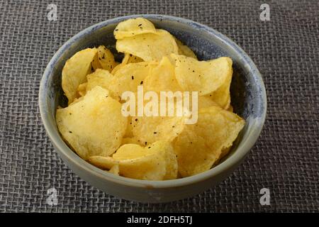 Italian Black Truffle Potato Chips in ceramic bowl on burlap Stock Photo
