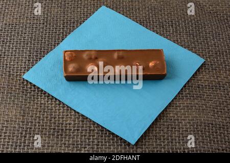 Hazelnut milk chocolate candy bar on blue napkin on burlap Stock Photo