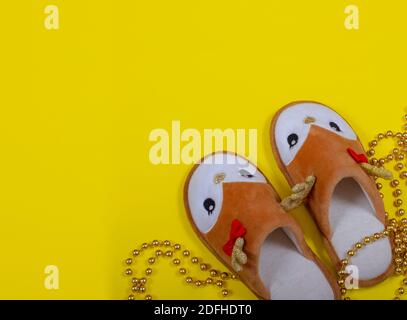 Sterling golden beads and home slippers in the form of a Christmas deer on a yellow background. Christmas and New Year concept. Stay at home. Stock Photo