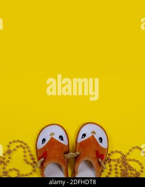 Sterling golden beads and home slippers in the form of a Christmas deer on a yellow background. Christmas and New Year concept. Stay at home. Stock Photo