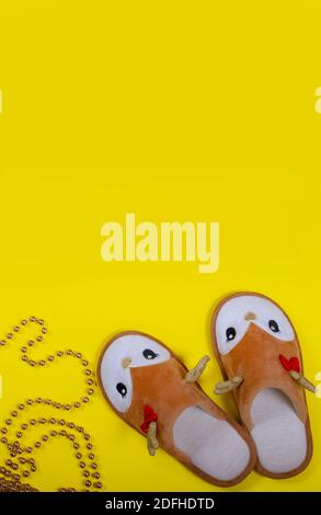 Sterling golden beads and home slippers in the form of a Christmas deer on a yellow background. Christmas and New Year concept. Stay at home. Stock Photo
