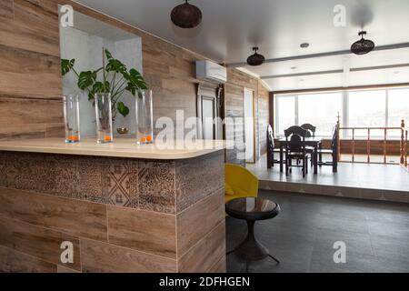 The interior space of the living space. Bar counter made of porcelain stoneware and wooden countertops. 3 glasses in the foreground. Stock Photo