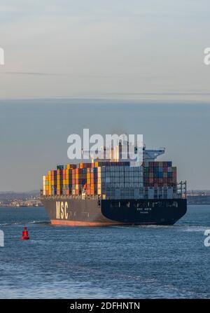 a large container ship MSC asya entering the port of southampton docks with a full cargo or load of colourful containers on board. Stock Photo