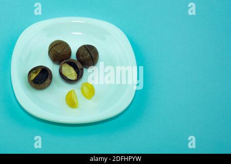 Macadam closed and open nuts on a white plate. Stock Photo