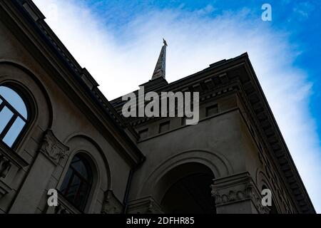 The old building is faced with brown marble and high metal spire on the roof. Stock Photo