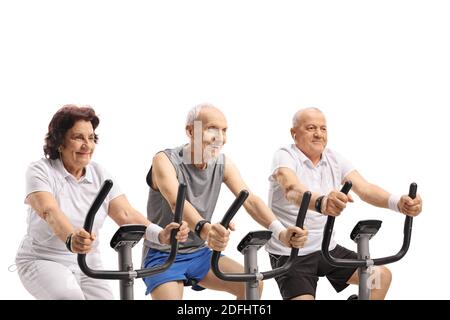 Elderly men and a woman riding stationary bikes isolated on white background Stock Photo