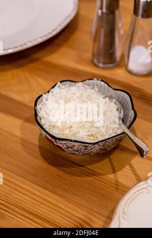 Grated Parmesan Cheese in Bowl on Wooden Surface at Kitchen. Traditional Organic Food. Stock Photo