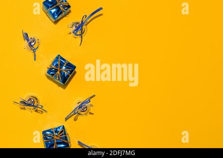 Christmas minimalistic composition. On a bright yellow background, boxes and bells, copy space. Celebratory template, postcard, greeting. Stock Photo