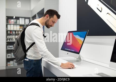 Belarus; December 05, 2020; blogger in store Apple Store examines new Apple iMac 27 5K, a man chooses a home computer in a store, the concept of a man Stock Photo