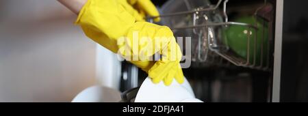 Hand in yellow glove take out washed kitchen utensil. Stock Photo