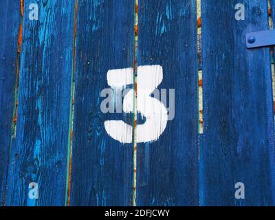 Number three on an old abandoned weathered blue colour wooden gate in Budapest suburb, Hungary Stock Photo