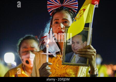 A woman holds a portrait of the Thailand's late King Bhumibol Adulyadej ahead of a candlelight vigil to remember the birthday of the Thailand's late King, outside the Grand Palace in Bangkok. Stock Photo