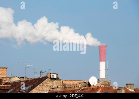 Belgrade, Serbia - December 1, 2020: Heating and power station chimney smokestack in red and white stripes, with smoke, in an old residential part of Stock Photo