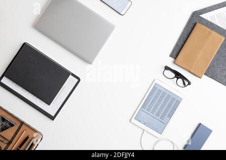 Flatlay of tablet, documents in clipboard, several notebooks in leather cover, eyeglasses, smartphone, envelope with paper and office supplies Stock Photo