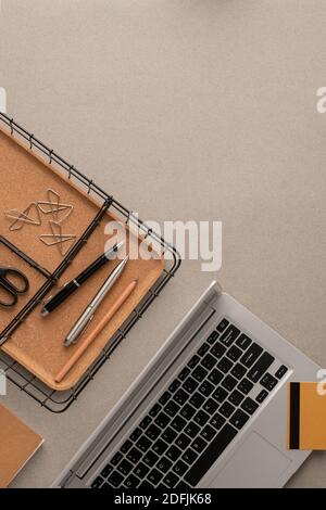 Flat layout of credit card over laptop keypad, basket with two pens and pencil, several clips and scissors with copyspace for text on the right Stock Photo