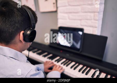 Child learning piano online lessons in quarantine . Coronavirus life style Stock Photo