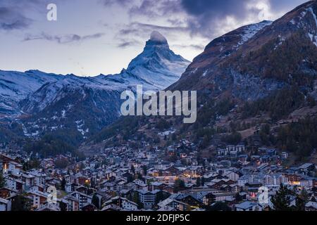 The Swiss village of Zermatt in Valais in autumn at dusk, with the Matterhorn and the Alpine mountain range in the background. Stock Photo