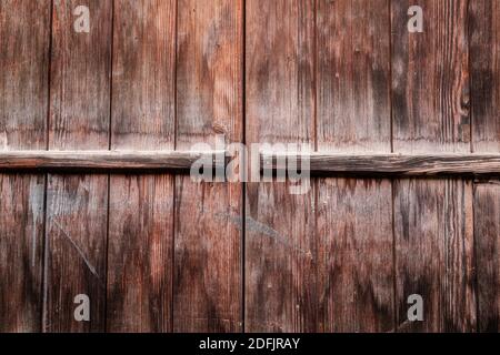 Dark brown weathered wooden plank wall of chalets in the old town of zermatt. Stock Photo