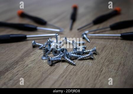 Seven screwdrivers and many screws on the table Stock Photo