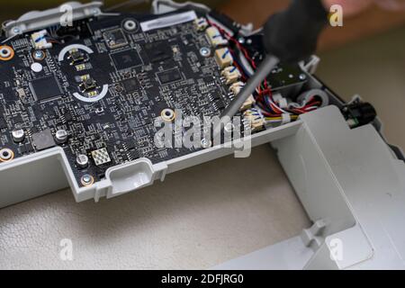 Electronic circuit board and wiring inside a modern robot vacuum cleaner. foreman repairs the device with a screwdriver Stock Photo