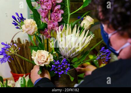 the owner of a flower shop working on a bouquet of flowers after reopening by covid Stock Photo