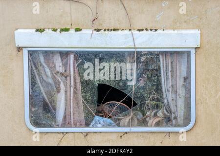 Broken window of an old derelict caravan. Stock Photo