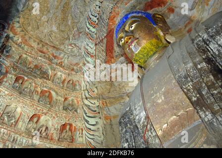 Yungang Grottoes near Datong in Shanxi Province, China. Large ancient statue of Buddha in a cave at Yungang with gold face and blue hair. Stock Photo