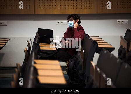 A student works in an amphitheatre at La Sorbonne University, at rue du Pantheon, in Paris, France, on October 13, 2020. One of France's largest public universities is adamant that it won't be 'imposing physical distance' on campus but says it has boosted efforts to protect staff and students from COVID-19. At Pantheon-Sorbonne University hand sanitizing dispensers have been installed, reusable masks are readily available and the timing of classes have been staggered as part of new measures which have been implemented amid the pandemic. Students of the university have been given the option to Stock Photo