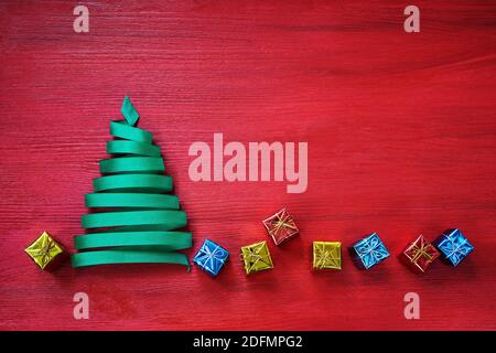 Christmas tree made from green ribbon with small gifts on a red background. Stock Photo