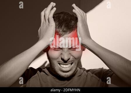 Man suffering from painful migraine or strong tension headache. Cluster headache, stress. Hands on head. Head pain in temples Stock Photo