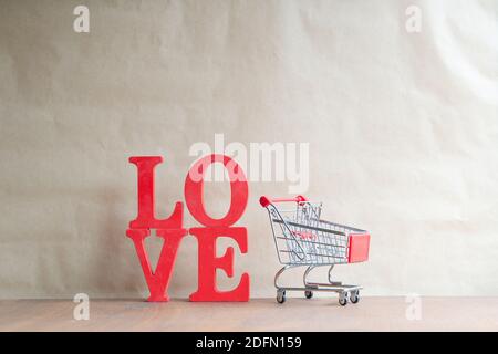 couple red heart shape in mini shopping cart on wooden table. love and shopping concept Stock Photo