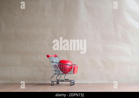 couple red heart shape in mini shopping cart on wooden table. love and shopping concept Stock Photo