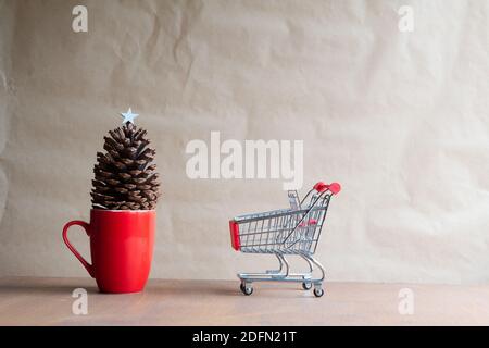 miniature Christmas tree in a cart from the store and an alarm clock on a winter window, the concept of Christmas sales Stock Photo