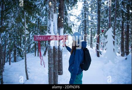 Vancouver, Canada, BC, January 1, 2018, Young woman is touching a sign 'Make a wish', entering a winter wonderland Stock Photo