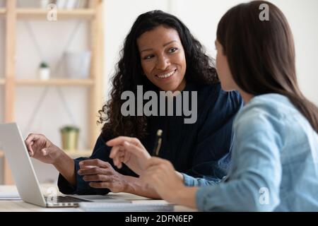 Smiling multiracial female colleagues cooperate in office Stock Photo