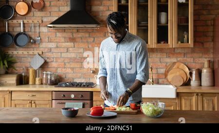 Happy young african american man enjoying cooking in kitchen. Stock Photo