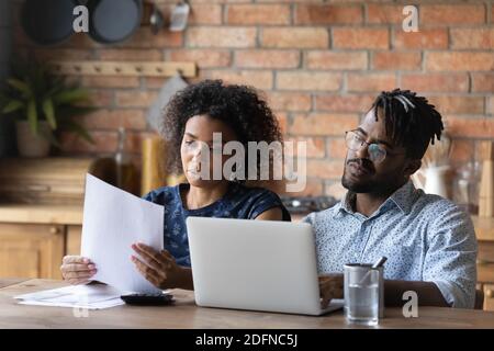 Focused young african american couple calculating monthly expenses. Stock Photo