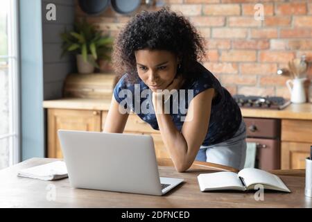 Smiling young african american woman working on computer at home. Stock Photo