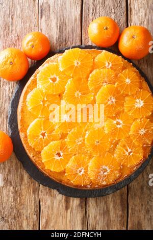 Sliced sponge tangerine pie close-up on a slate board on the table. Vertical top view from above Stock Photo