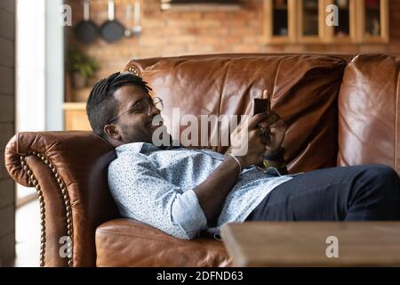 Happy relaxed young african american man using smartphone. Stock Photo