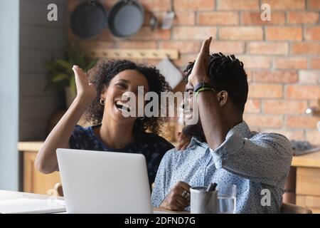 Emotional euphoric young mixed race couple giving high five. Stock Photo