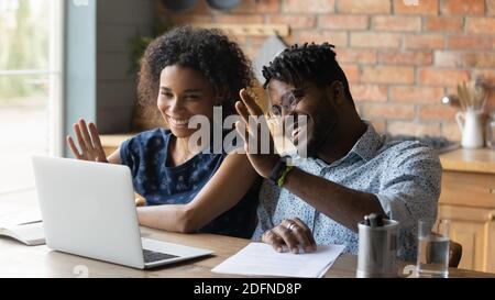 Happy positive young mixed race family couple holding video call. Stock Photo