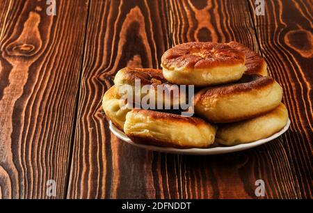 Homemade pastries, belyashi, in a plate on a wooden table Stock Photo